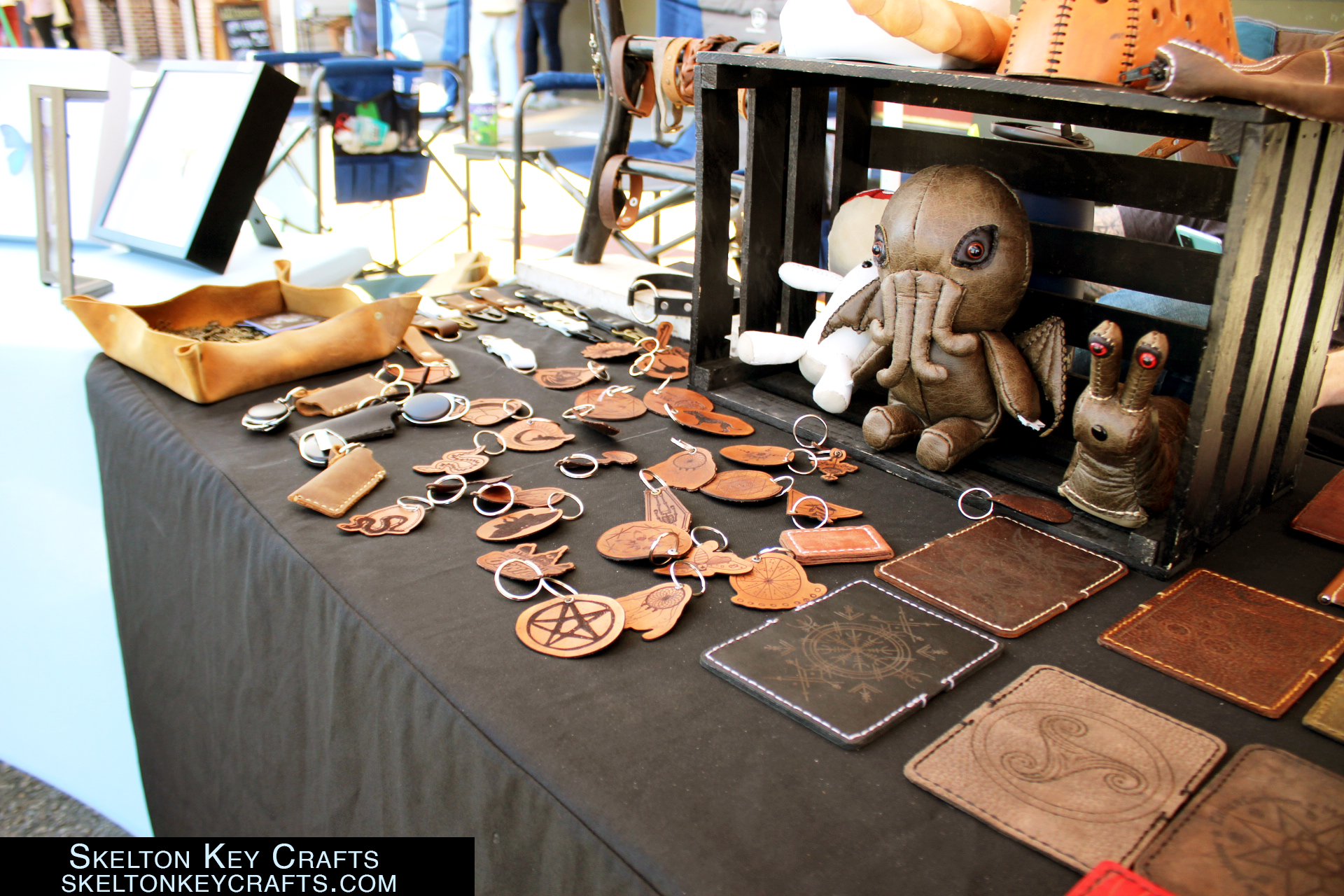 Multiple keychains made of leather and a Cthulhu plushie made of leather, a snail plushie made of leather, and small leather prints. 

Skelton Key Crafts