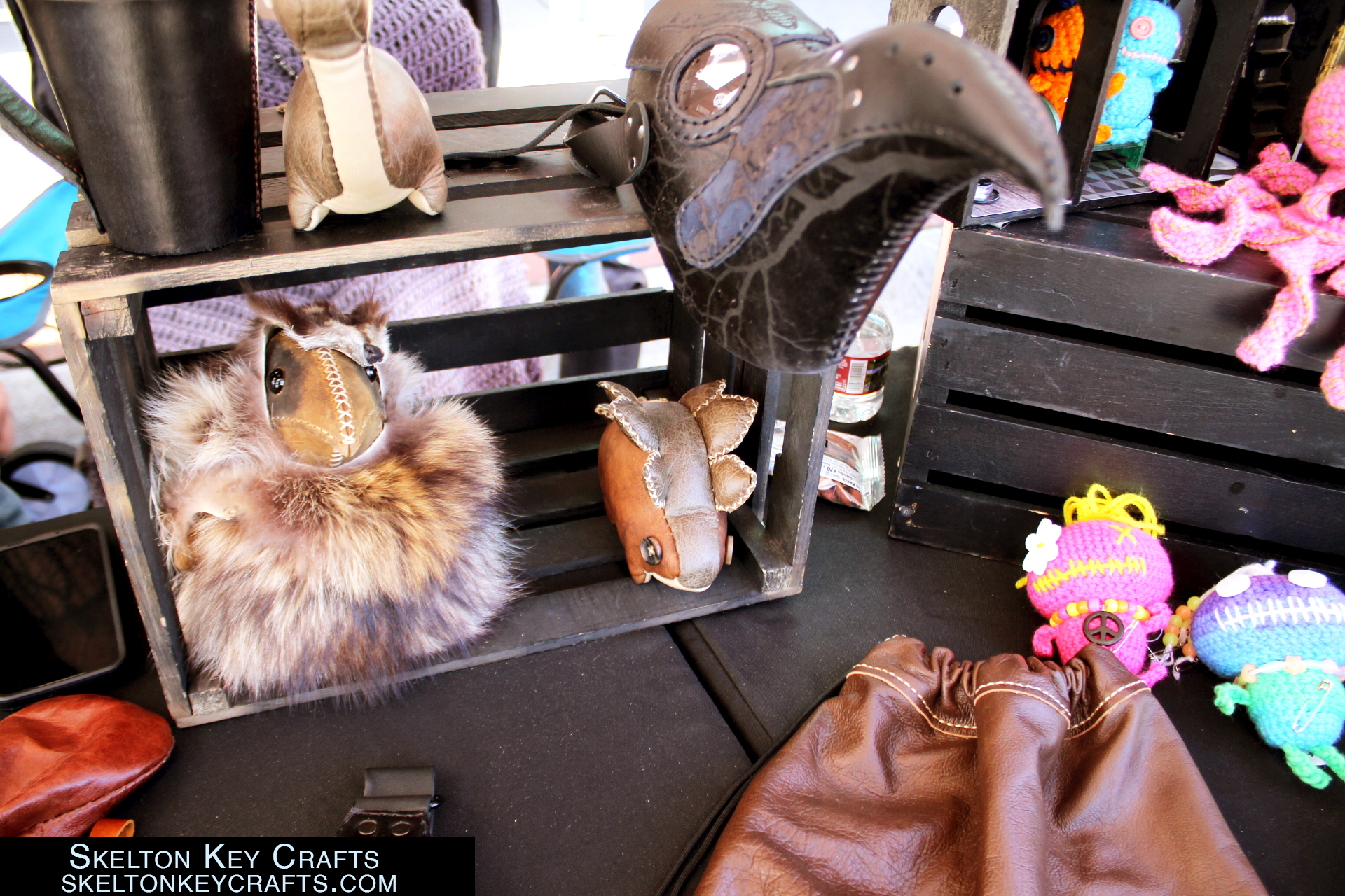Leather bags and plushies and voodoo dolls crocheted on display. 
